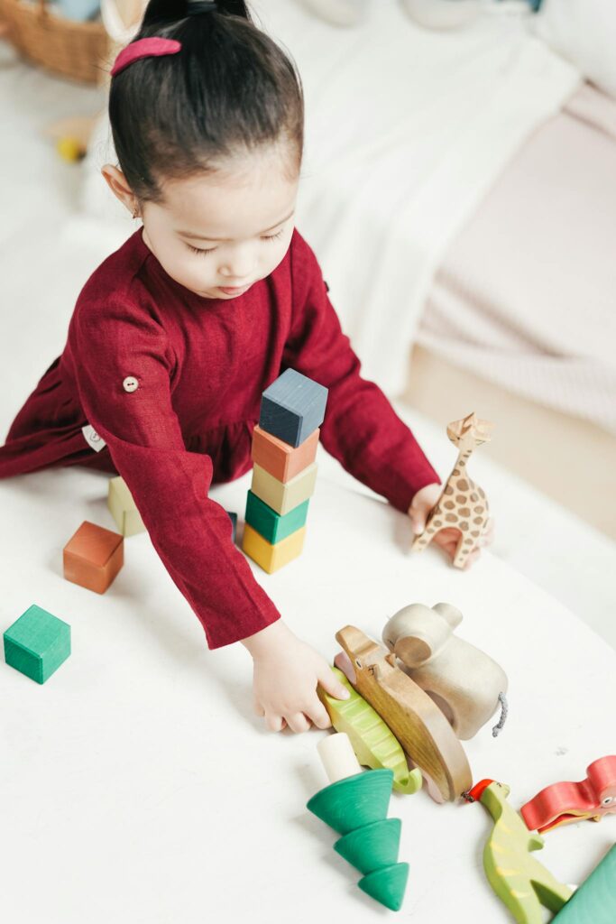 Young girl enjoying playtime with colorful wooden toys at home.
